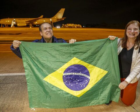 Casal segura bandeira do Brasil ao desembarcar de primeiro voo de resgate da FAB